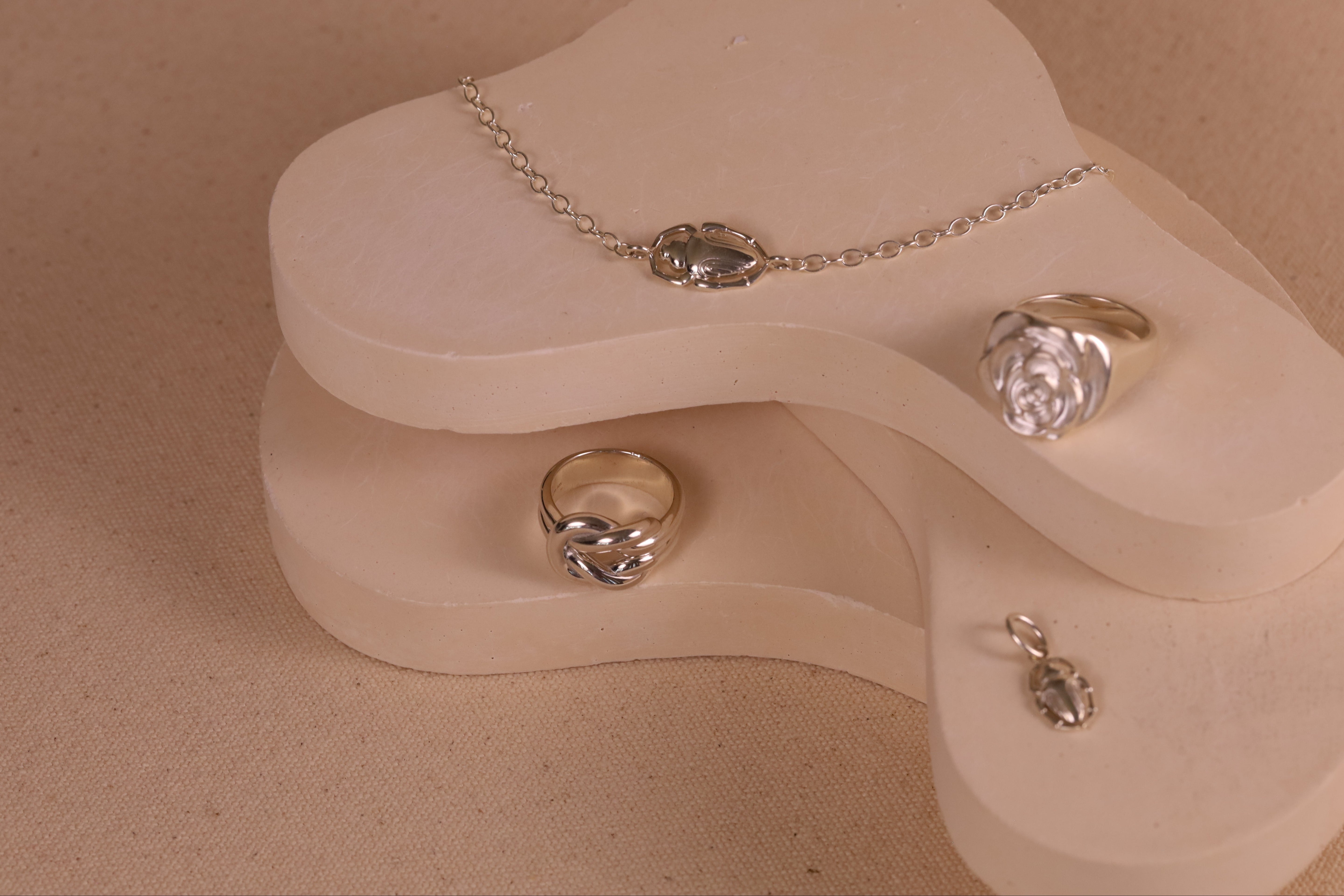 Sterling Silver collection including a lover's knot ring, rose signet ring, scarab bracelet, and scarab charm.