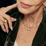 Close-up of a person wearing a gold necklace with a pendant, with a focus on jewelry details.