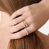 Close-up of a hand wearing multiple diamond rings on a neutral background