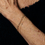 Close-up of an elderly person's wrist with a gold bracelet on a black background