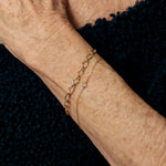 Gold bracelet on a person's wrist against a dark background