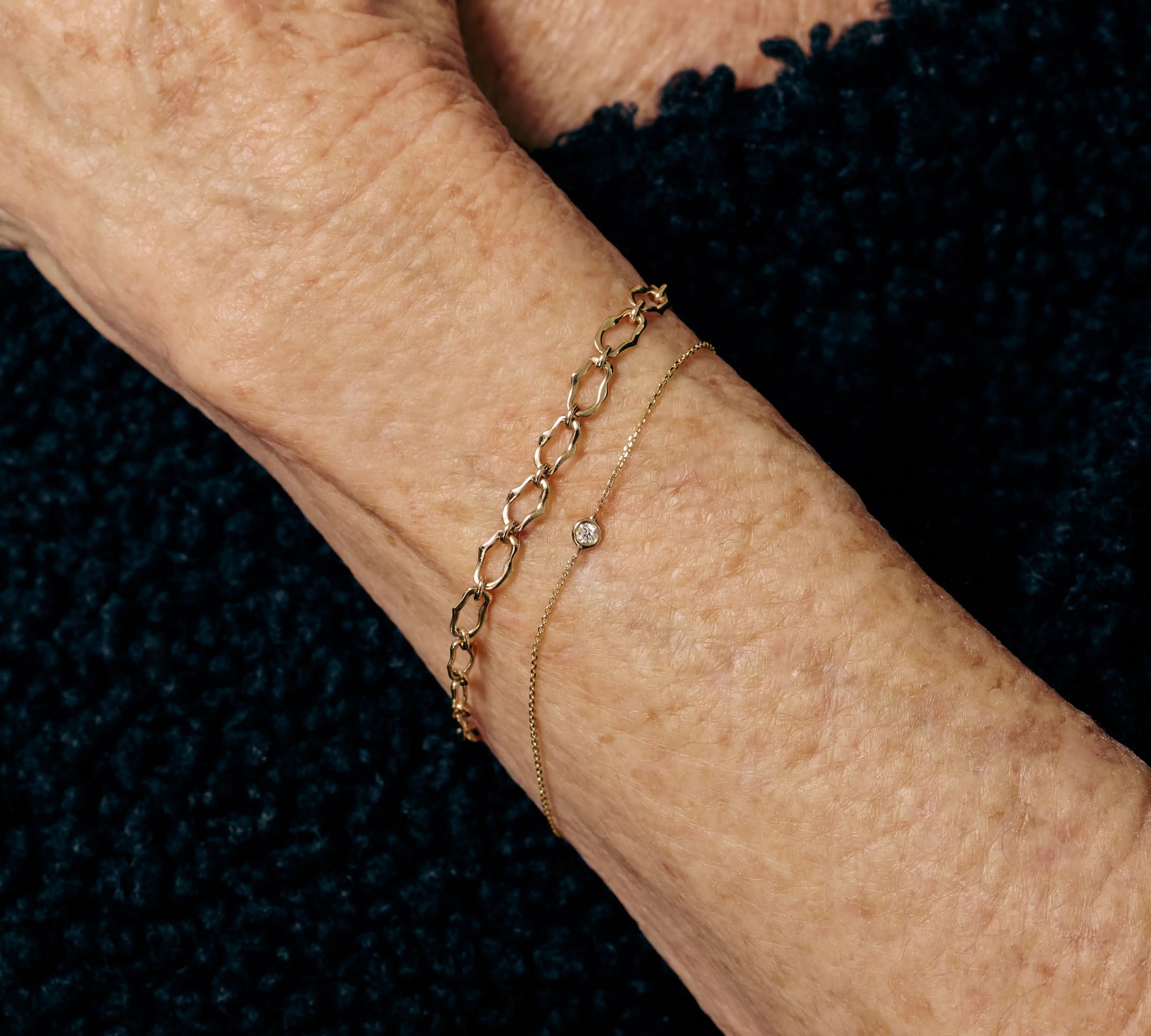 Gold bracelet on a person's wrist against a dark background
