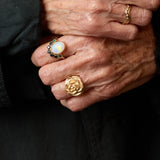 Close-up of hands wearing gold rings with a dark background