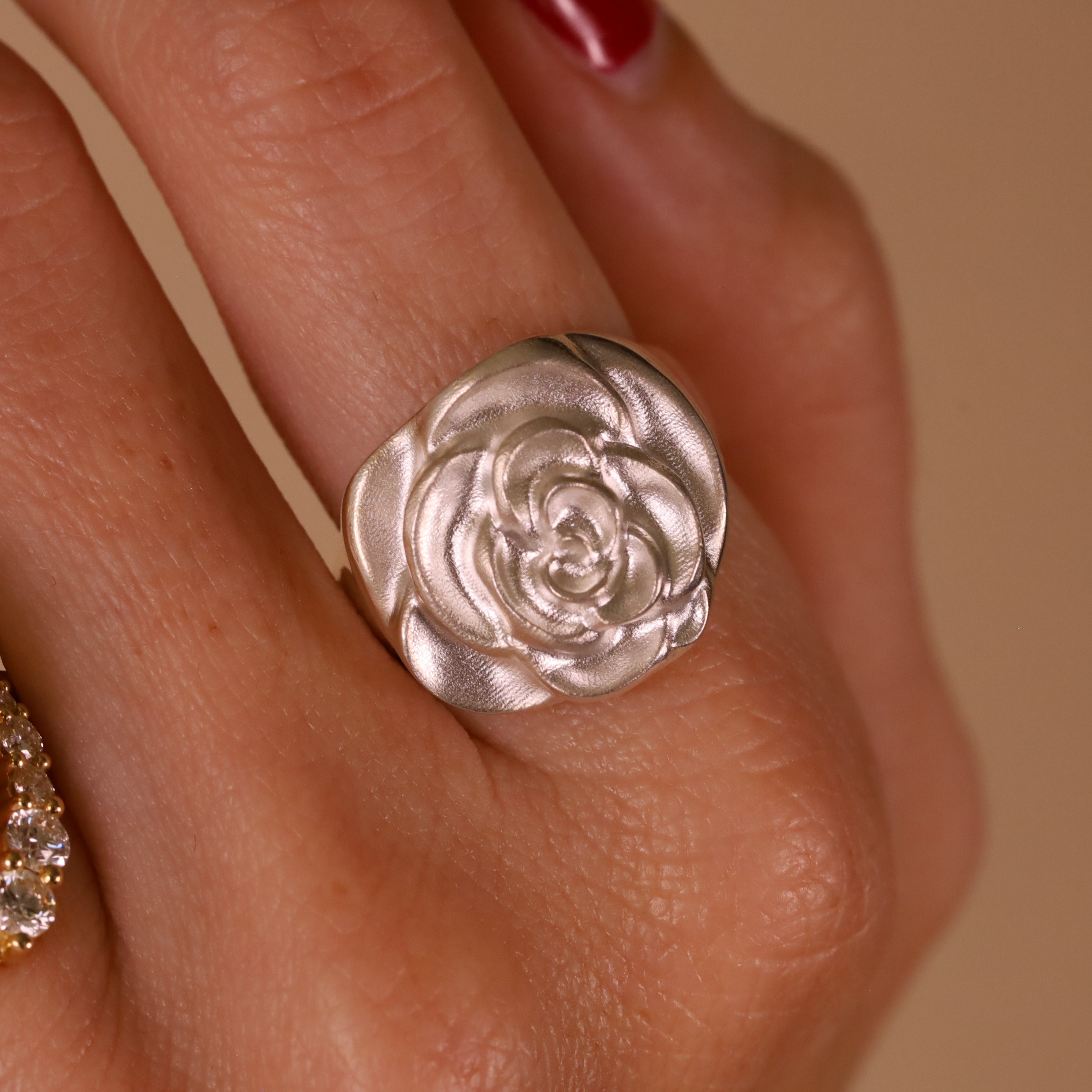 Hand wearing large sterling silver rose-shaped ring