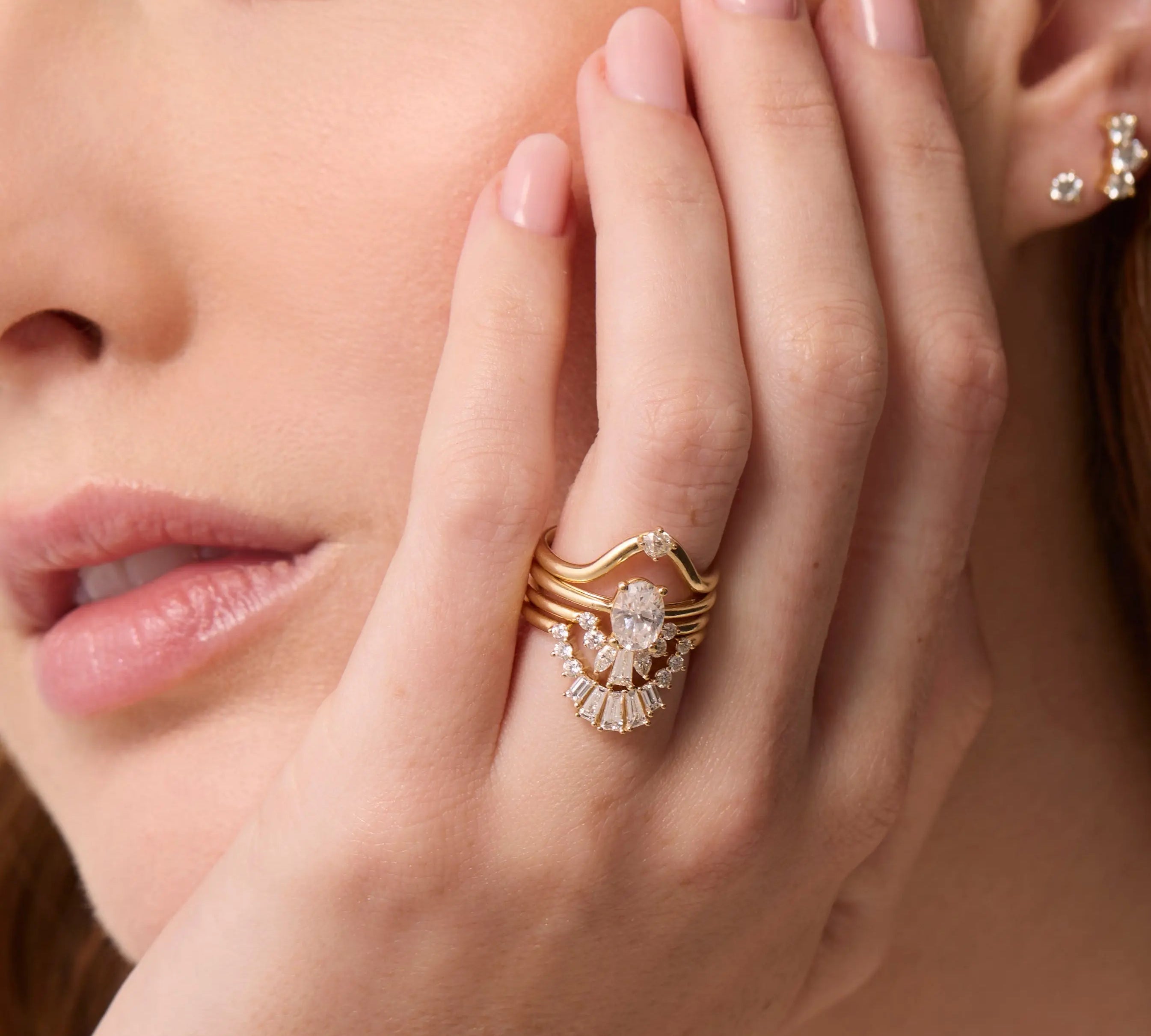 Close up of woman's resting on her jaw, highlighting multiple Marrow Fine diamond rings stacked together