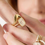 Close-up of a hand wearing a gold ring with a diamond, with another ring visible.