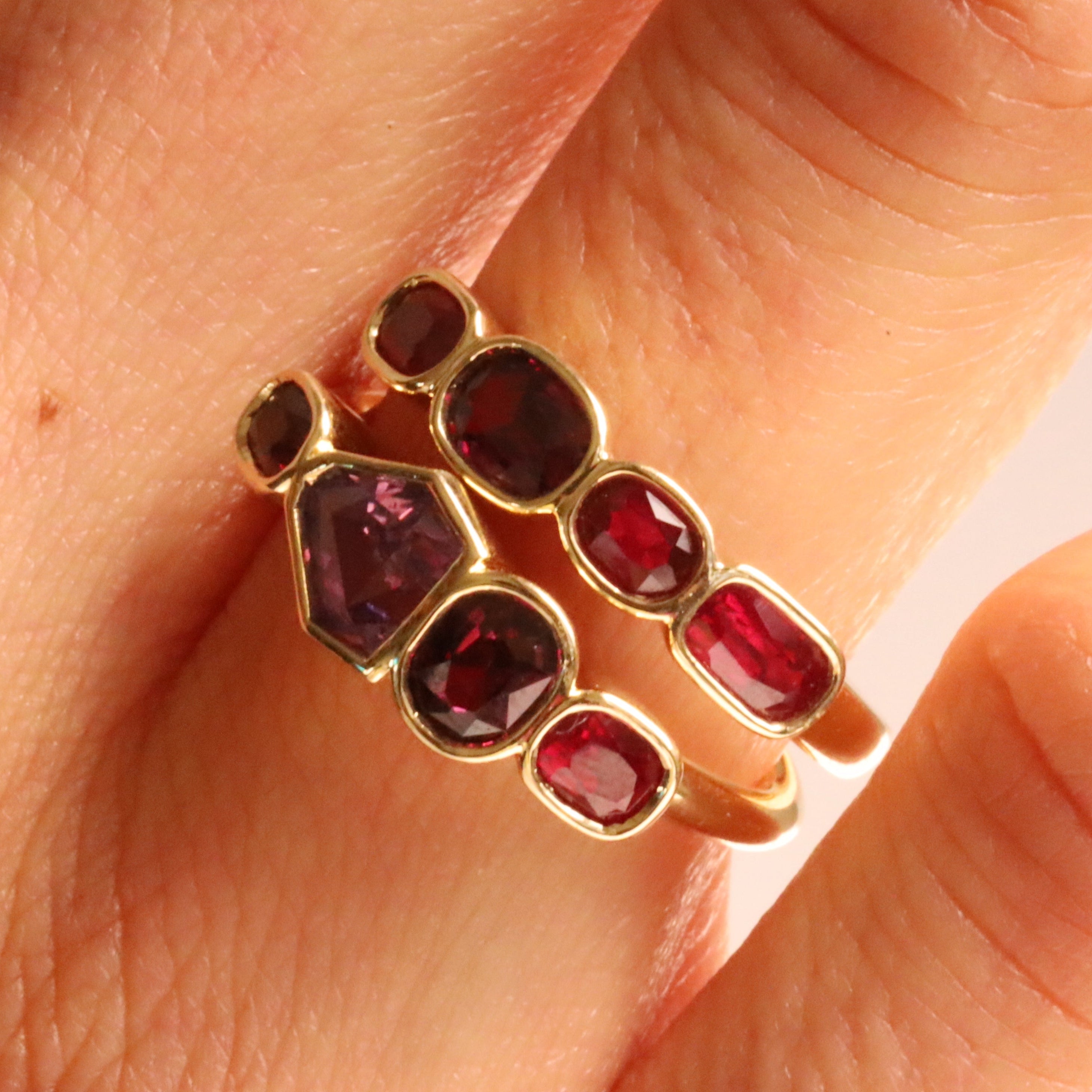 Close up of f 1.00tcw Ruby and 0.90ct Sapphire Linear Band and 1.20ctw Ruby Linear Band stacked on woman's hand