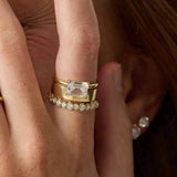 Gold ring with emerald-cut diamond on a finger
