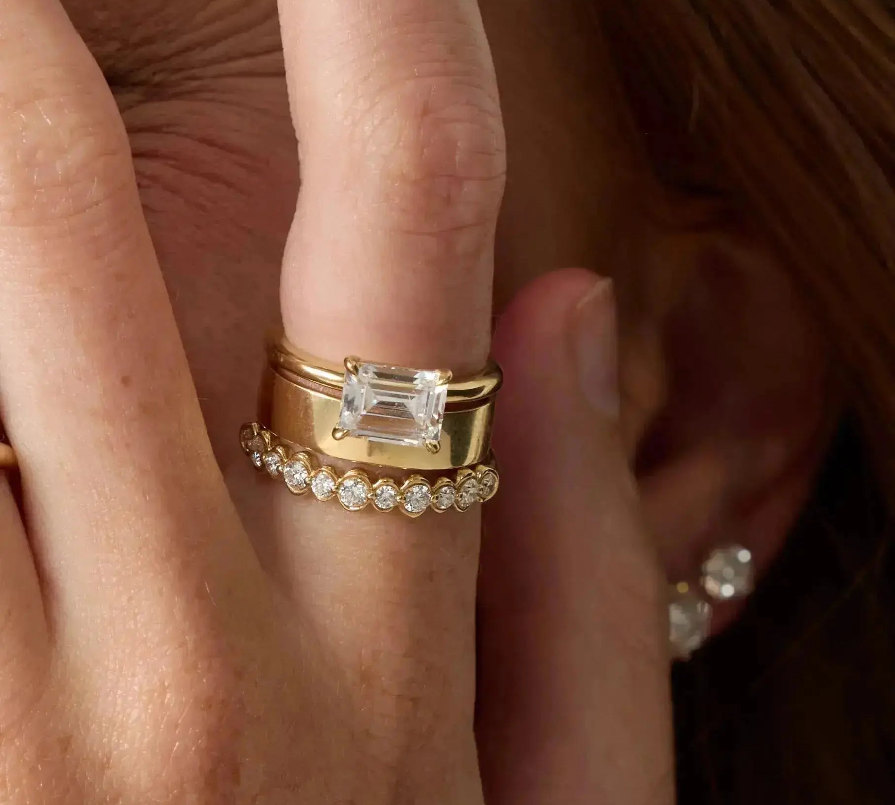 Gold ring with emerald-cut diamond on a finger