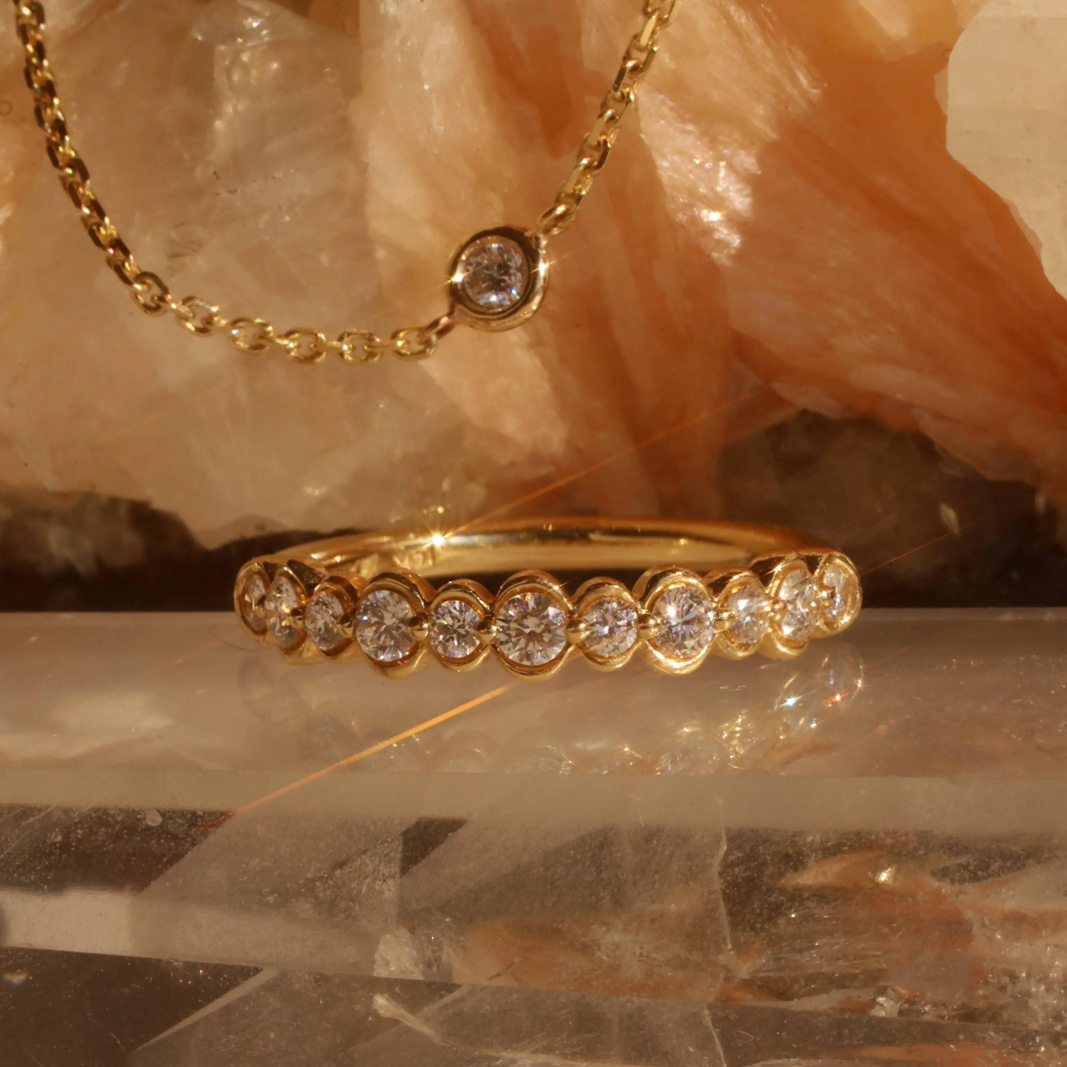 Gold ring with diamonds on a reflective surface with a stone background