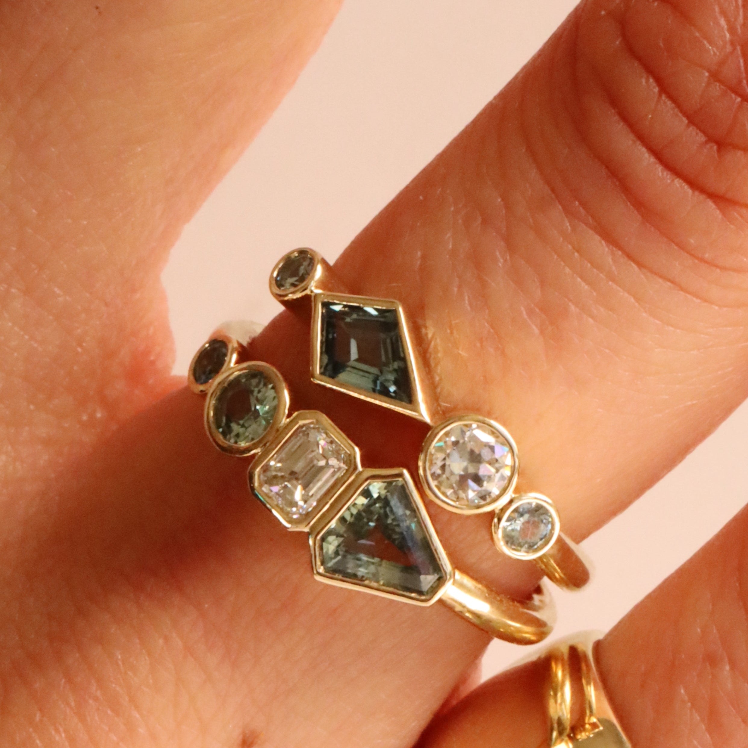 Close up of 0.48ctw Sapphire and White Diamond Linear Band + 0.79tcw Sapphire and White Diamond Linear Ring stacked o woman's hand