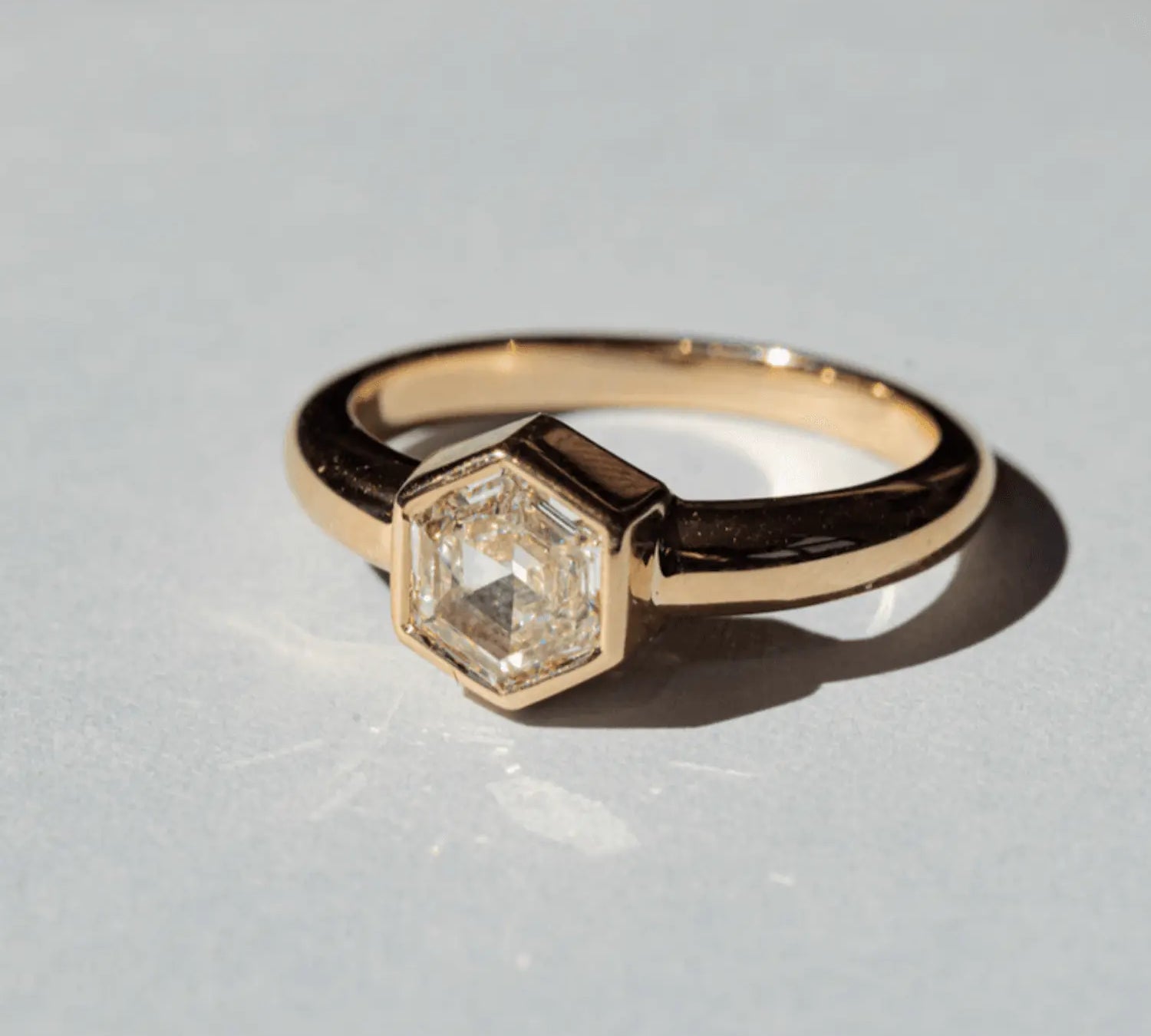 Image of a Marrow Fine one of a kind diamond solitaire ring. The center white diamond is a hexagon cut and bezel set in 14k yellow gold. 