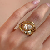 Gold ring with a large diamond on a finger against a beige background