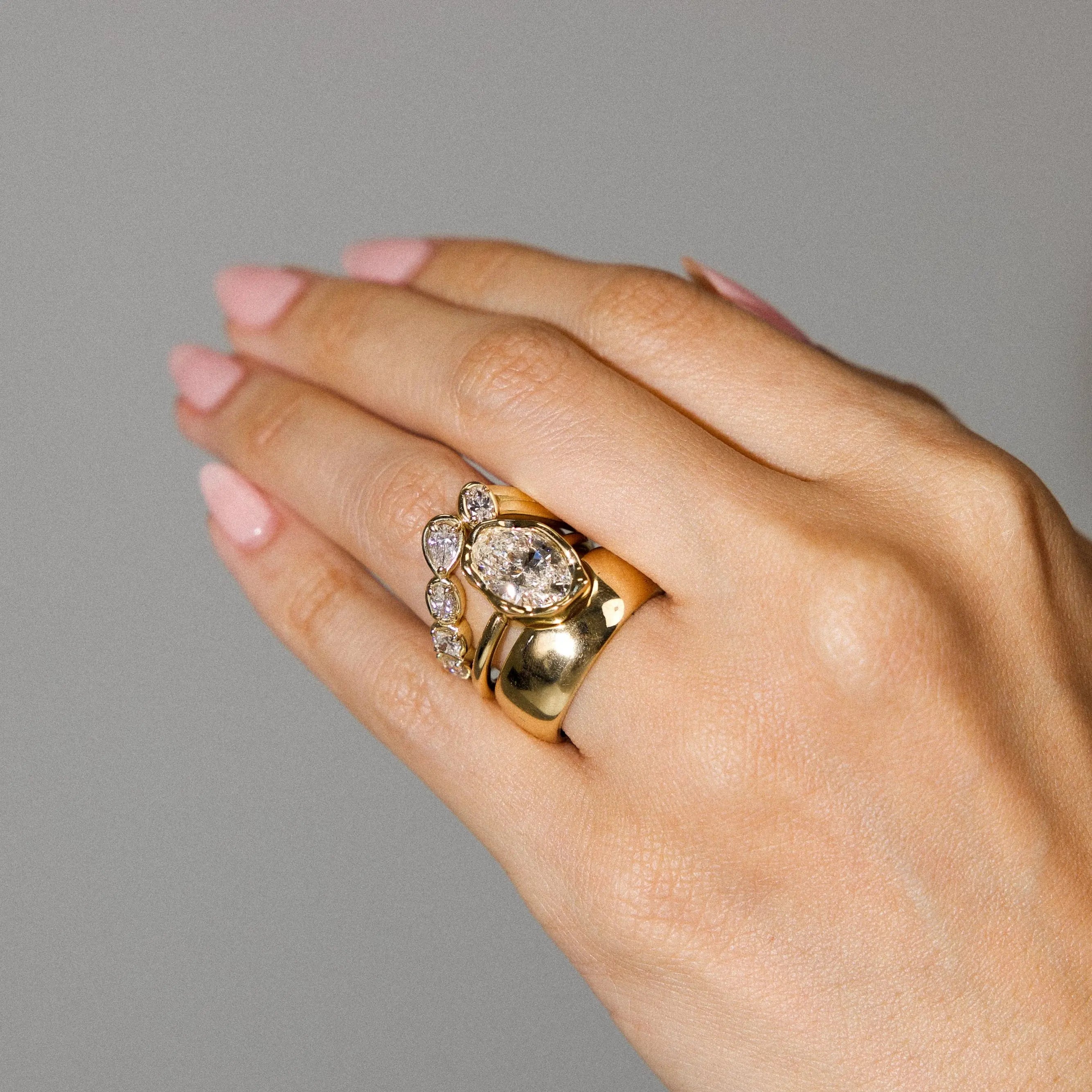close up of woman's hand wearing gold and diamond rings