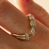 close up of woman's finger with a yellow gold asymmetrical ring that features different diamond cuts (pear oval, cushion)