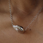 Pearl necklace on a person's neck with a neutral background