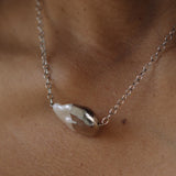 Pearl necklace on a person's neck with a neutral background