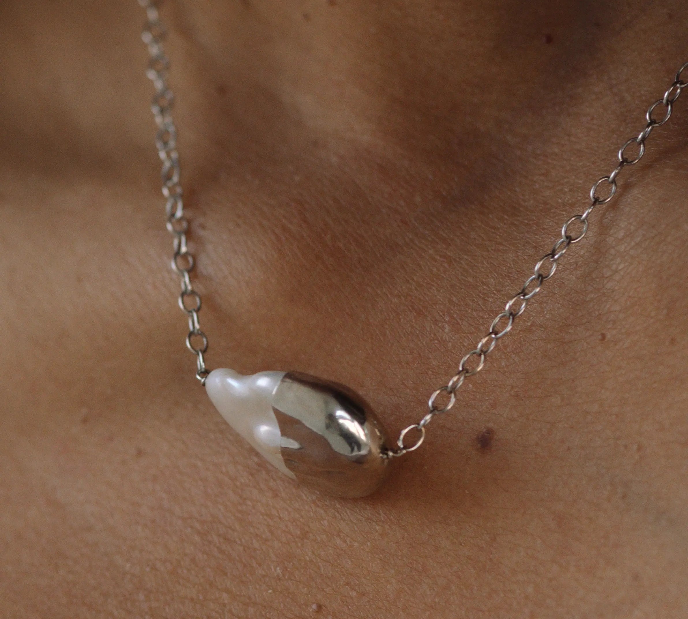 Pearl necklace on a person's neck with a neutral background
