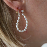 Pearl hoop earrings worn by a person with blonde hair.