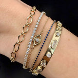 Close up of wrist with multiple gold and diamond bracelets stacked together