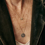 Necklace with an eye-shaped pendant worn by a person against a dark background