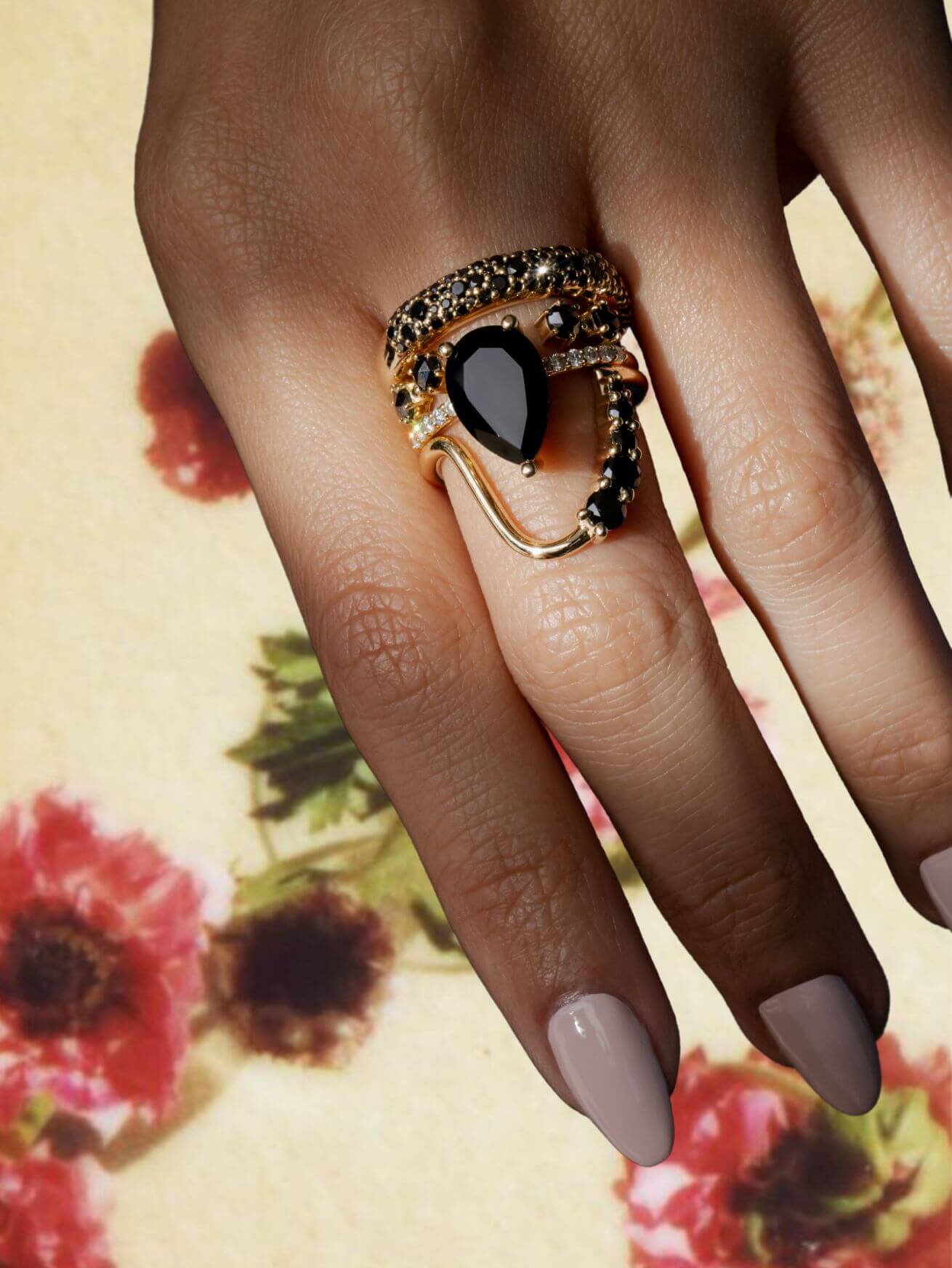 Close up of hands with black diamond and onyx ring stack with background removed over flowers.
