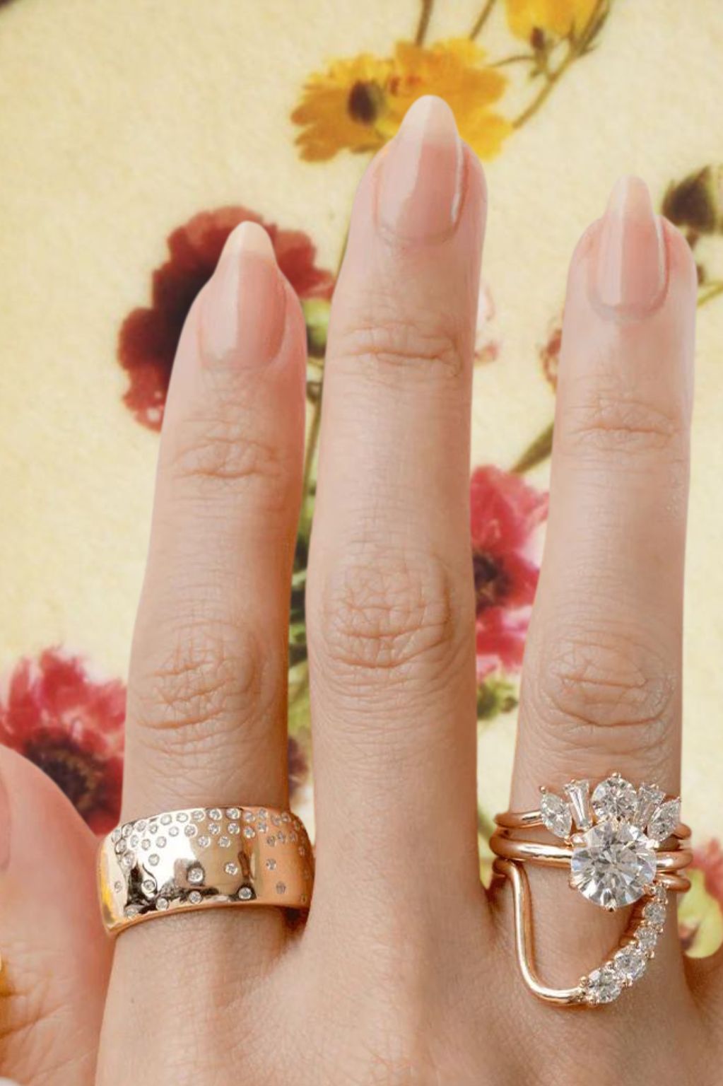 Close up of hand with Marrow Fine ring stacks against a floral background