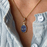 Swan Carving with 3.8mm Pearl Charm worn on the neck – two swans with necks forming a heart, carved in white on violet agate in 14k yellow gold, with a pearl floating in an open gold ring