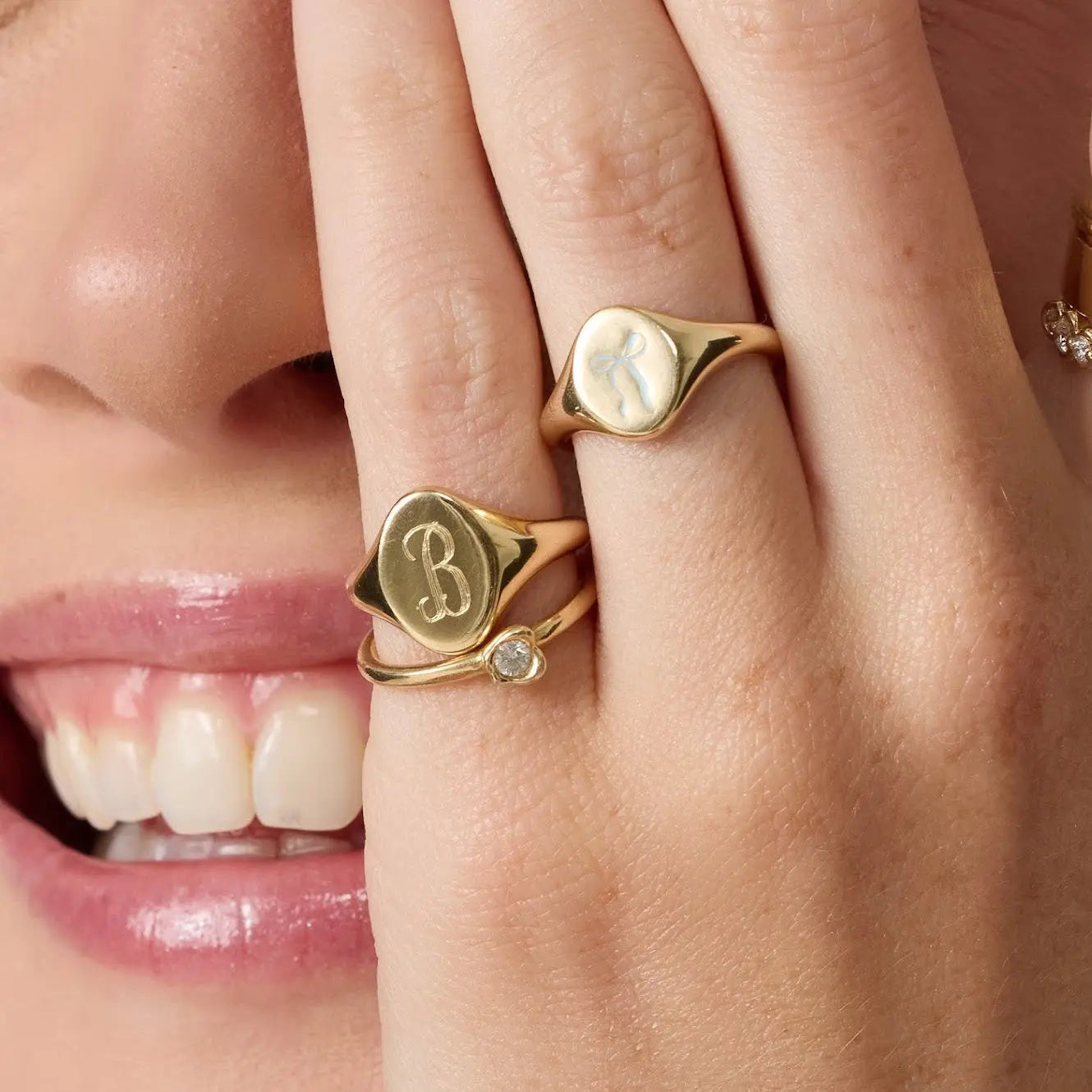 Close-up of a person wearing gold rings with initials on their fingers.