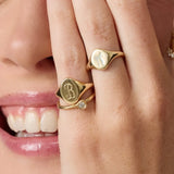 Close-up of a person wearing gold rings with initials on their fingers.