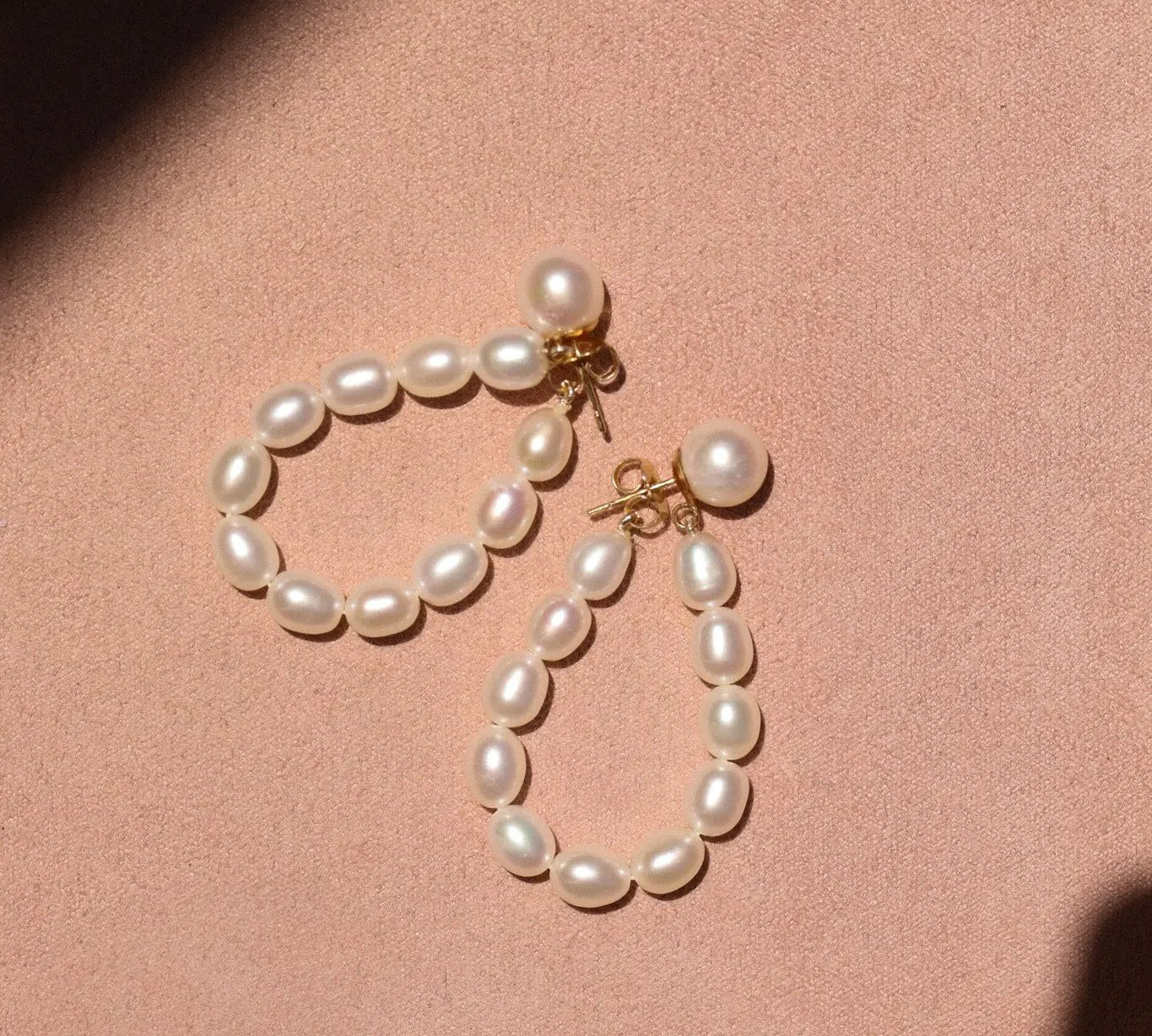Pearl earrings on a pink background