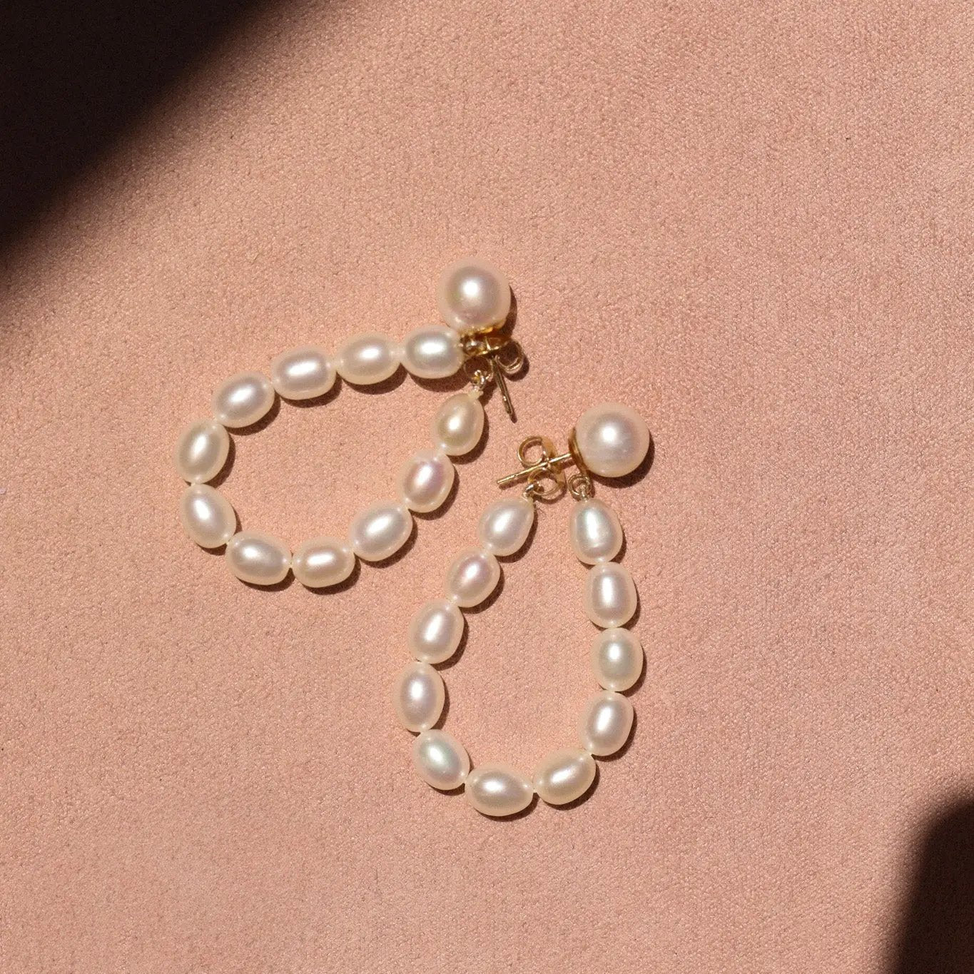 Pearl earrings on a pink background