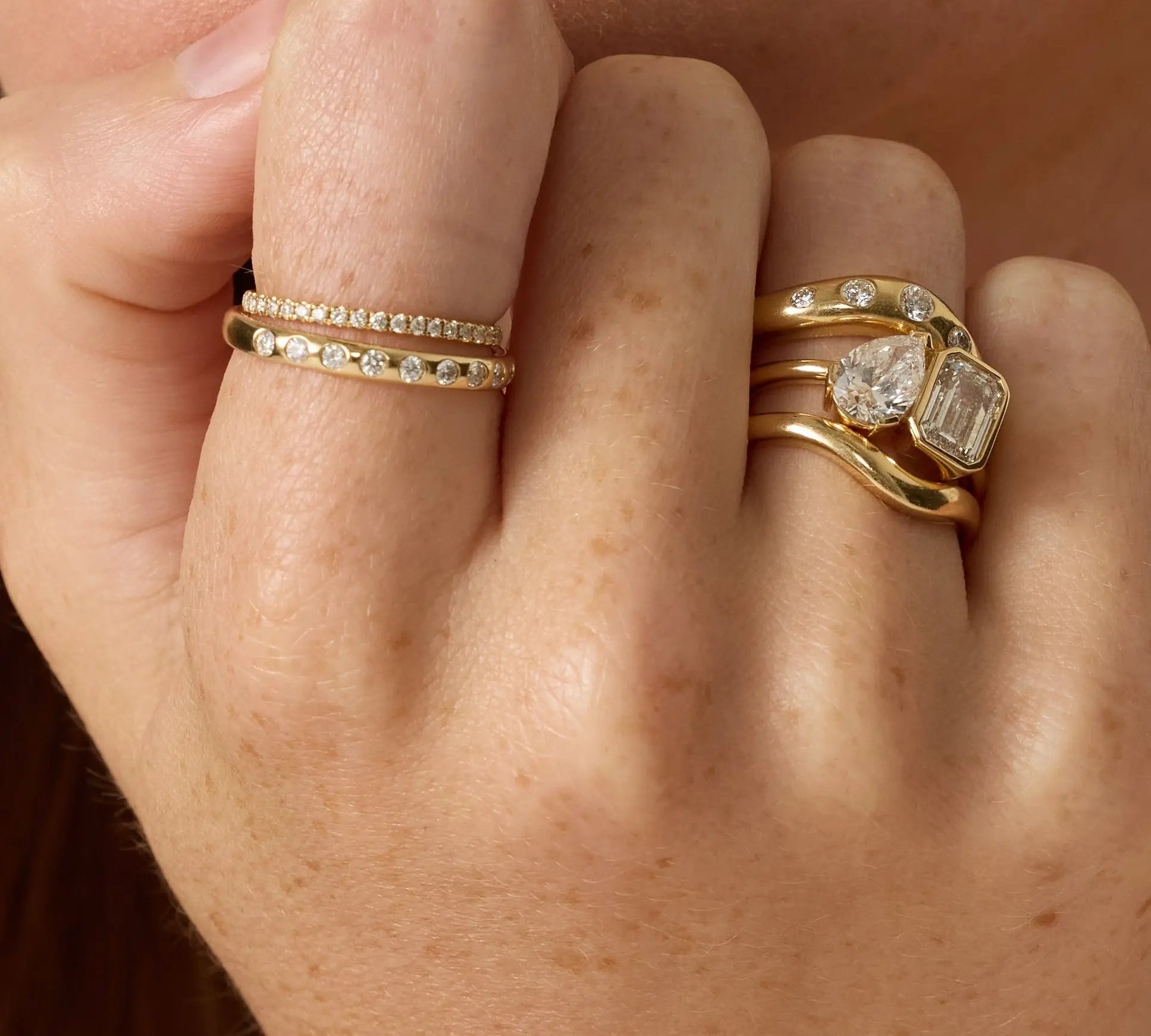 Close-up of a hand wearing two gold rings with gemstones.