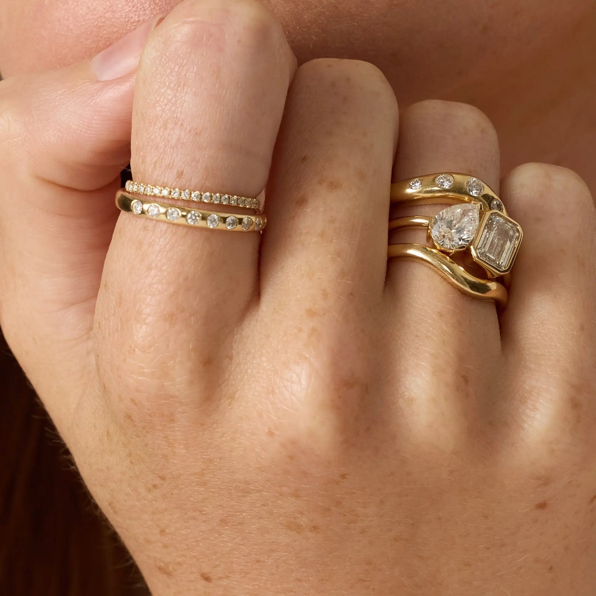 Close-up of a hand wearing two gold rings with gemstones.