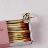 Gold ring with a diamond on top of an open matchbox