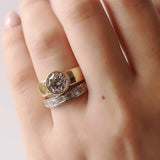 Close-up of a hand wearing two diamond rings on a light background