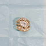 Yellow gold ring with pear-shaped diamond on a light blue textured background