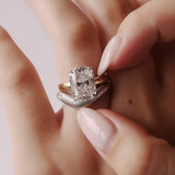 Close-up of a hand wearing a diamond ring with a light background