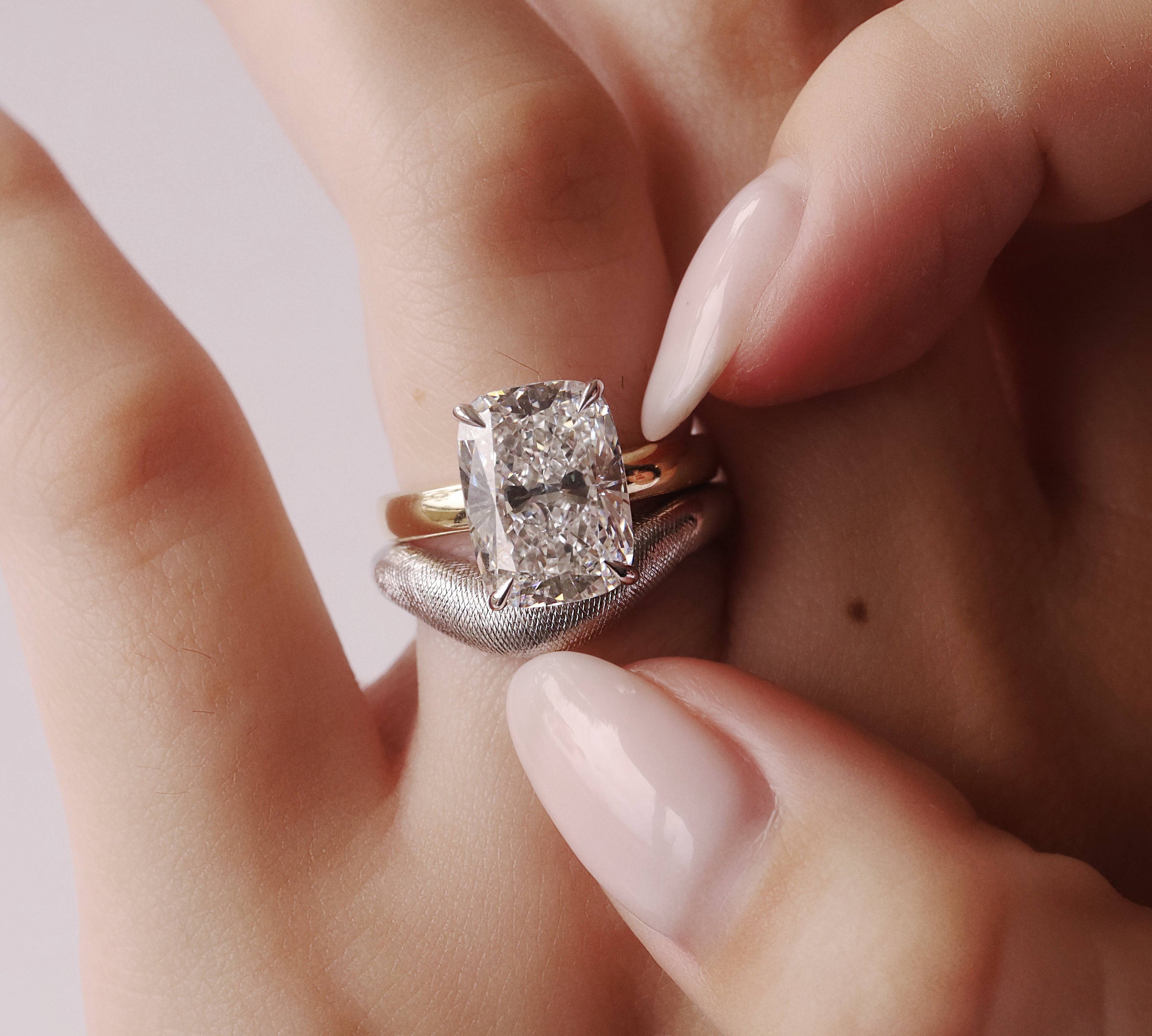 Close-up of a hand wearing a diamond ring with a light background