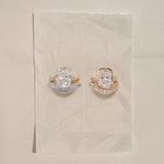 Two diamond rings on a beige fabric background
