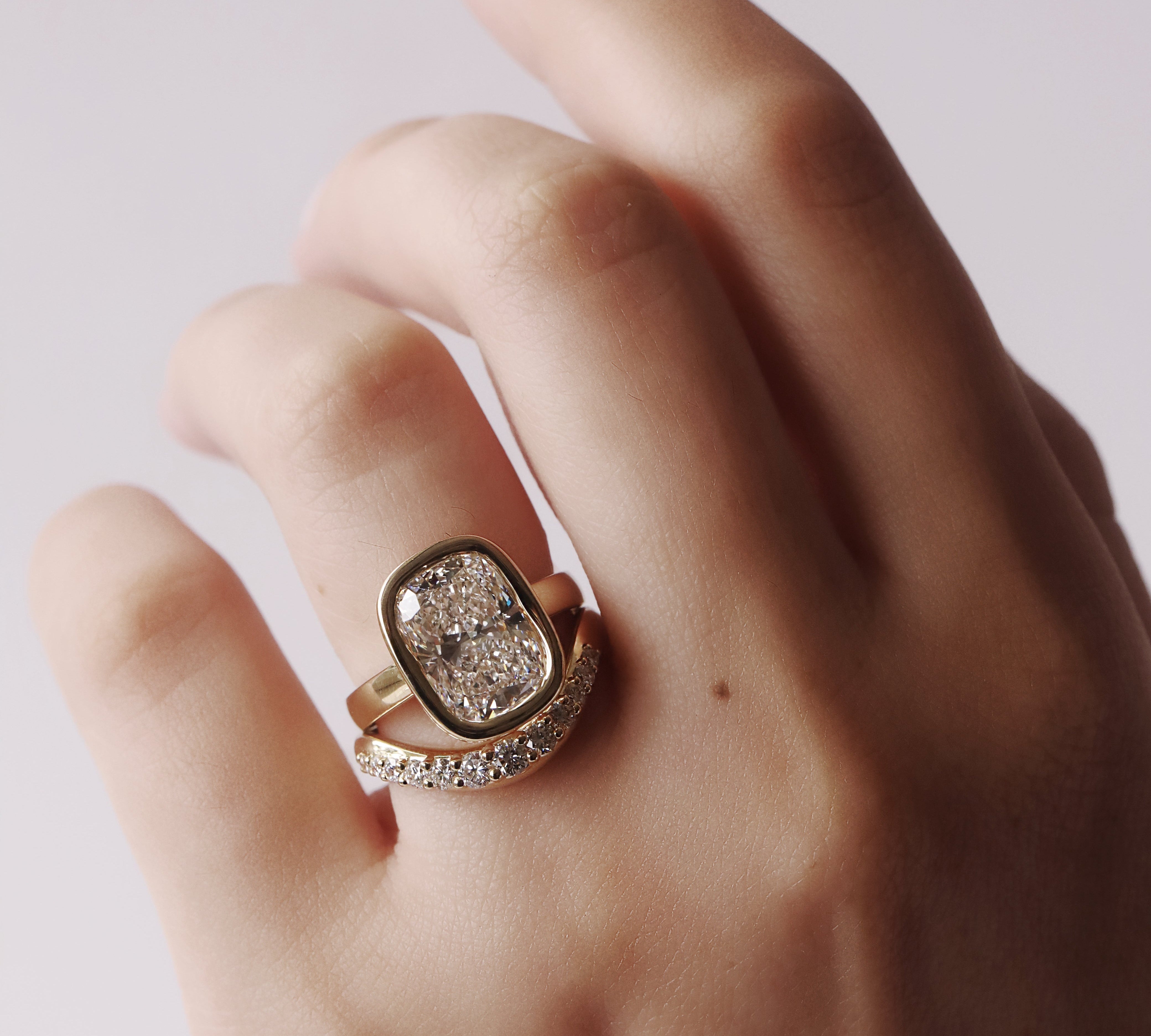 Hand wearing a diamond ring on a plain background