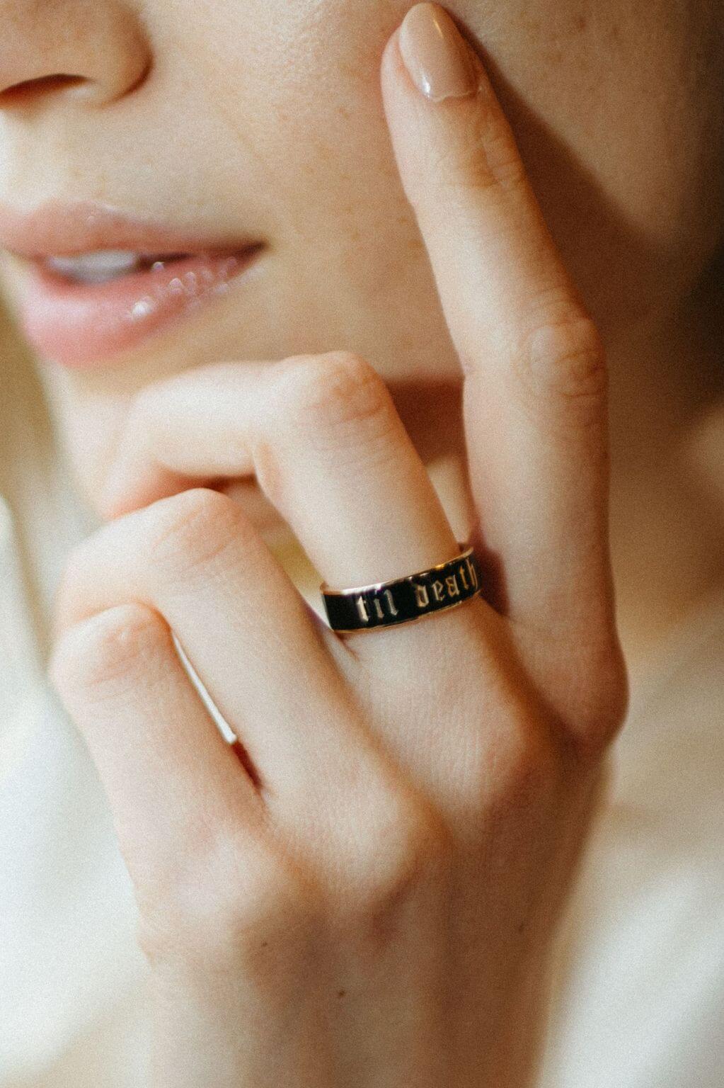 close up of woman's hand resting against her face with a Til Death Enamel Band on her middle finger