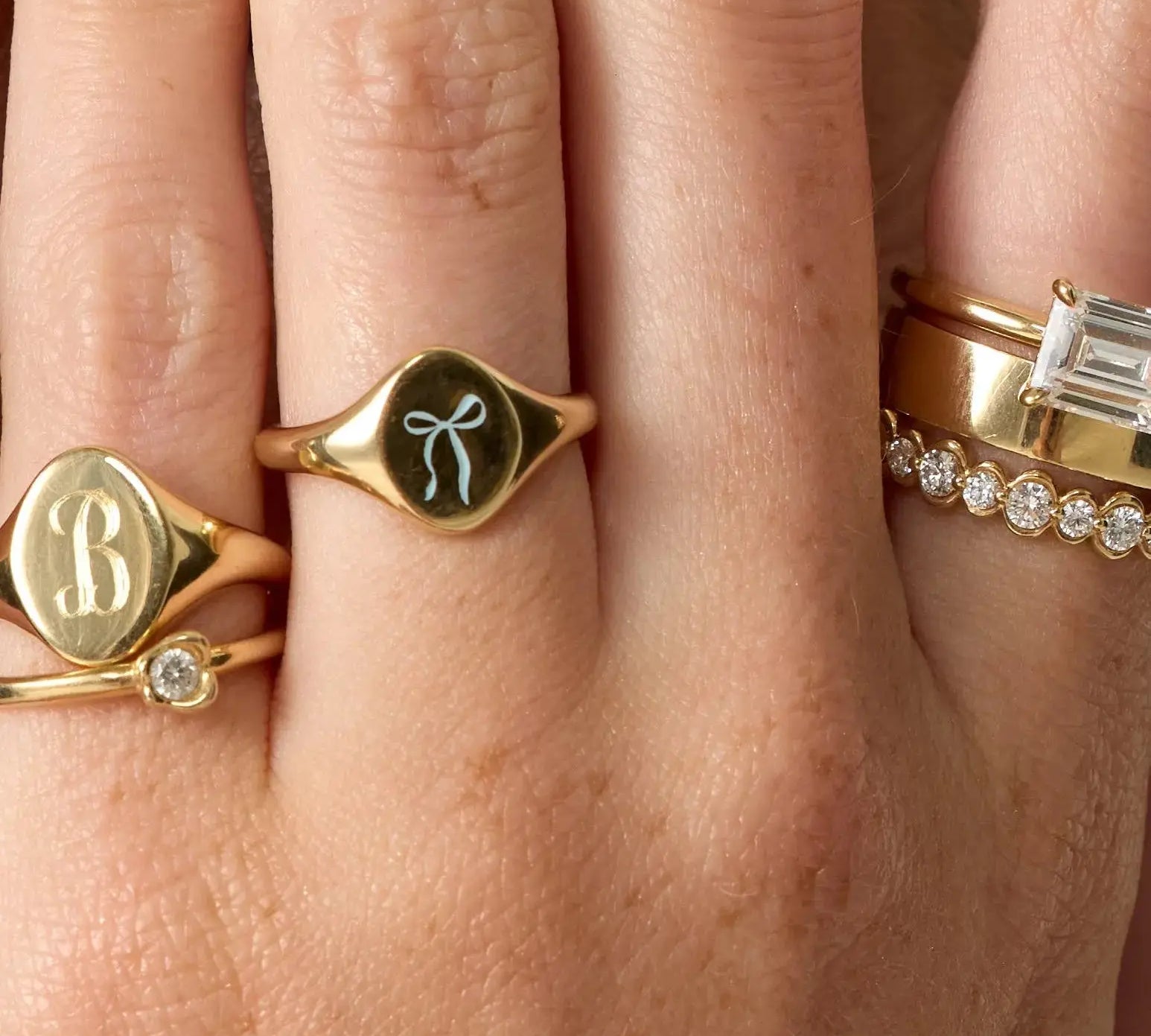 Close-up of a hand wearing multiple gold rings with different designs.