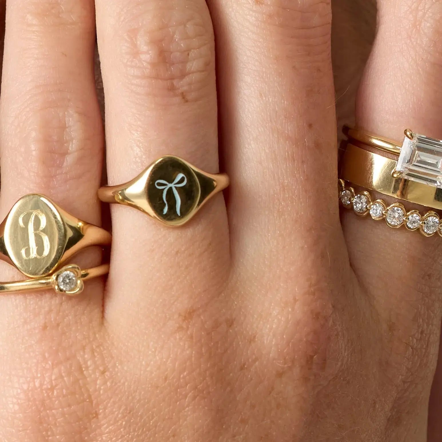 Close-up of a hand wearing multiple gold rings with different designs.