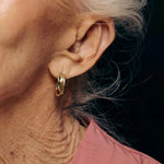 Close-up of an ear wearing a gold hoop earring with a dark background