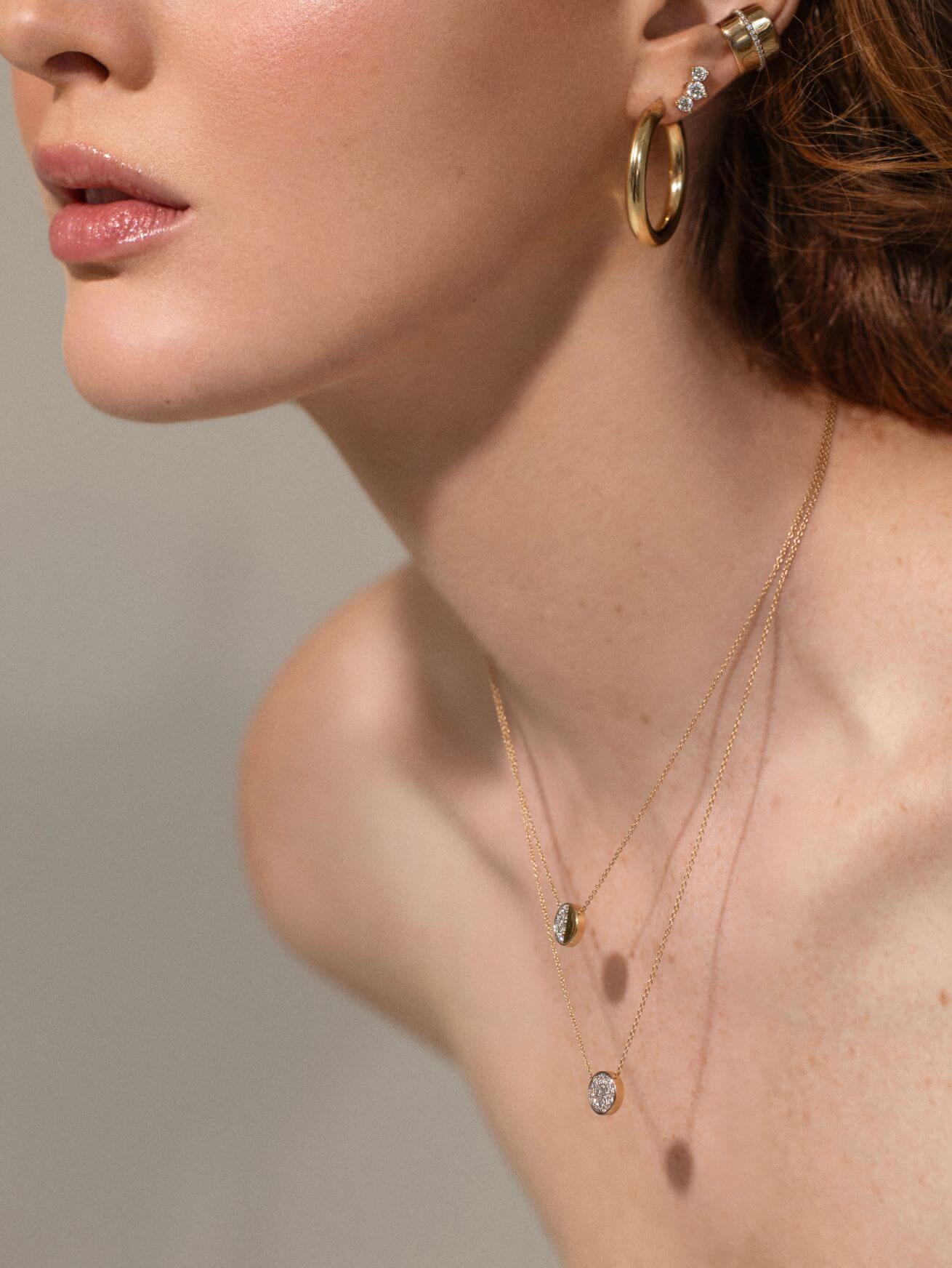 close up of woman wearing Marrow earrings and 2 layered Moon Phase pendants