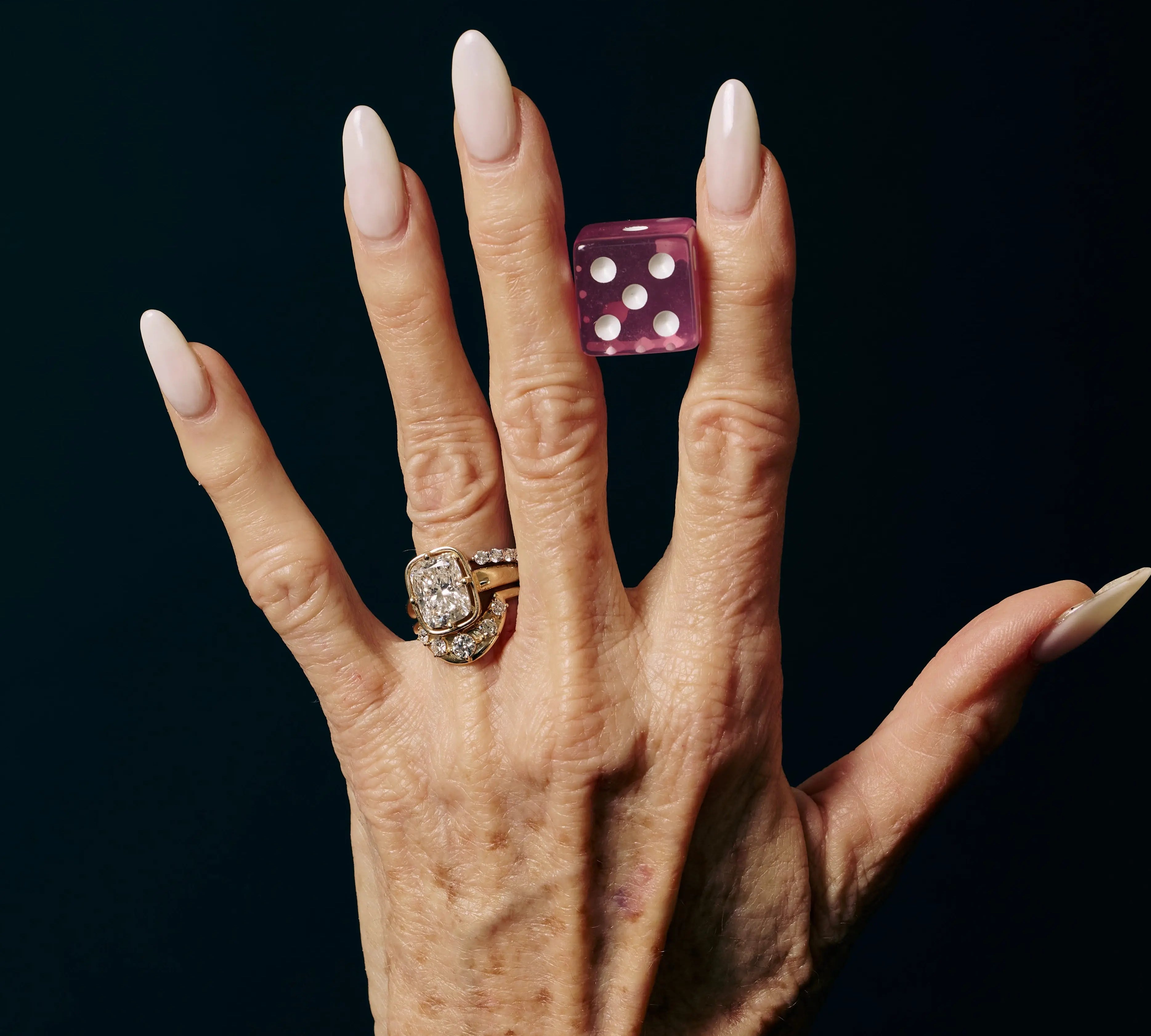Hand wearing a ring with diamonds on a black background