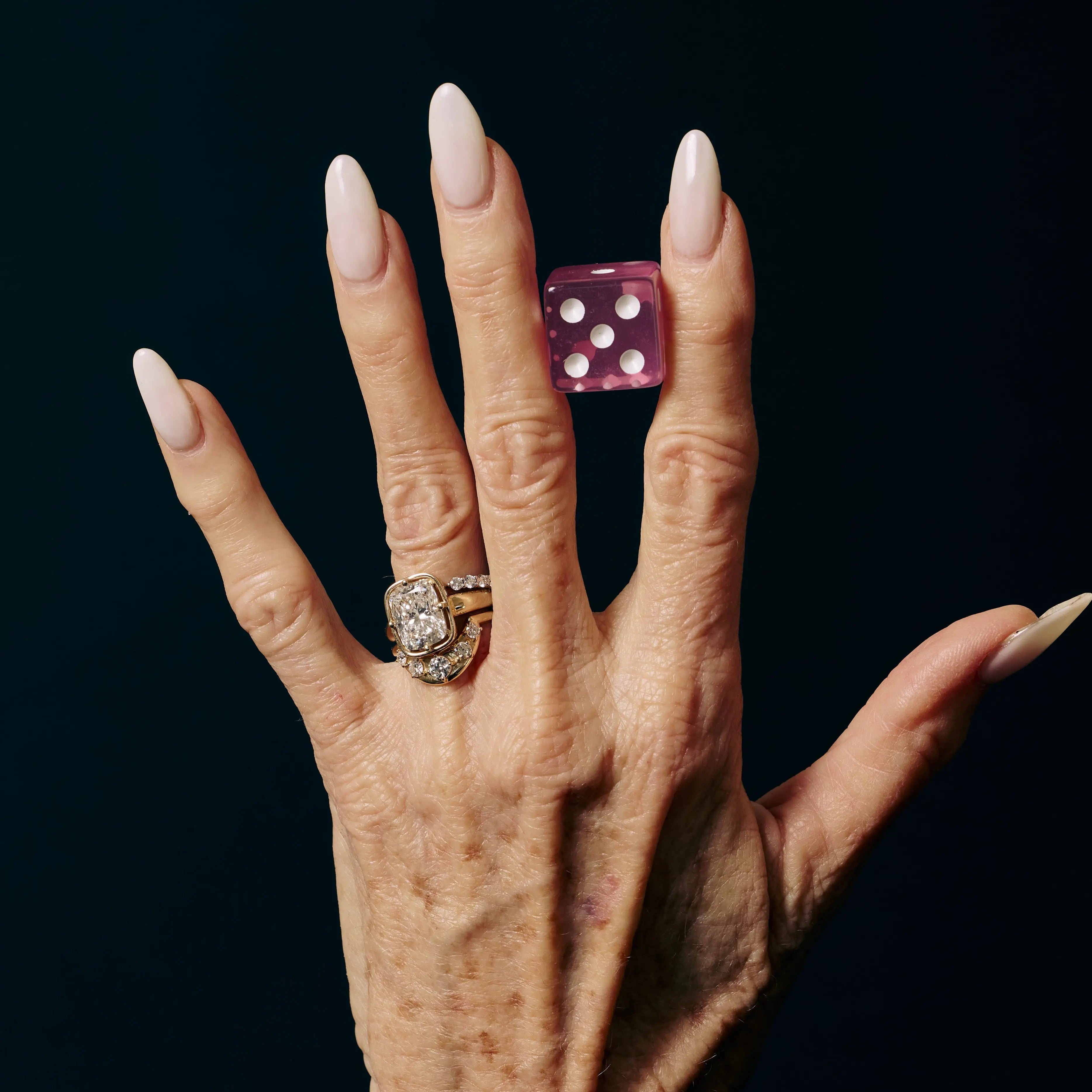 Hand wearing a ring with diamonds on a black background