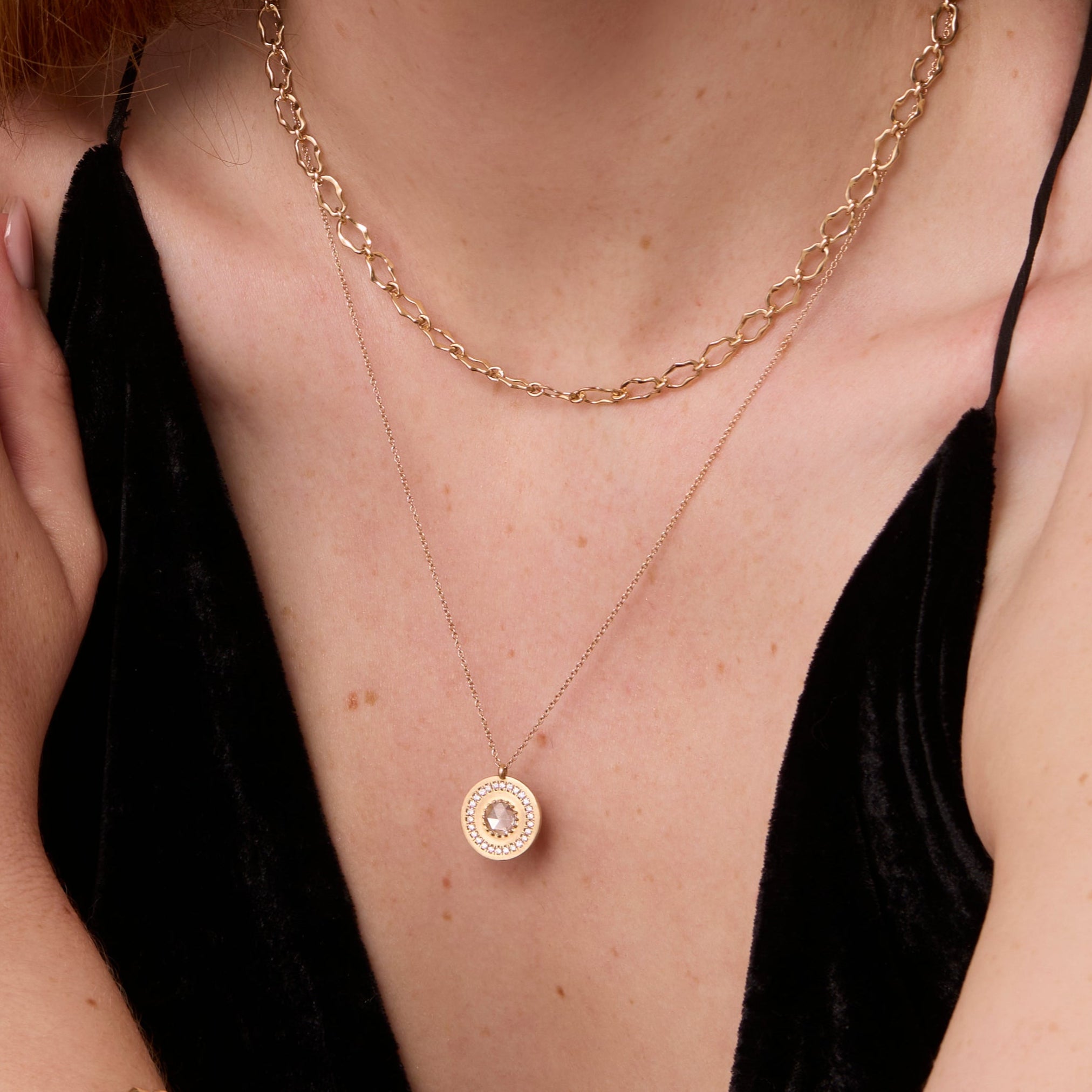 Close up of White Diamond La Femme Amulet on woman's décolletage 
