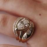 Gold ring with a large diamond and smaller diamonds on a person's finger